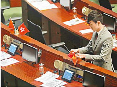  郑松泰把议员座席上的国旗和香港特区区旗倒转（图源：香港文汇网）