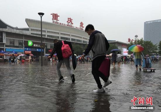 资料图:重庆降雨致地面积水,市民冒雨淌水前行。 周毅 摄