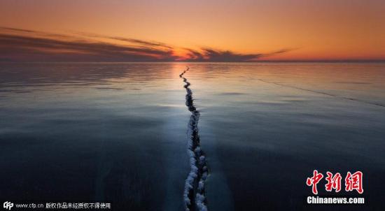 2015年4月1日消息，俄罗斯贝加尔湖面结冰，数百米长的裂缝仿佛将世界一分为二，夕阳的余晖洒在湖面上景色神奇迷人。图片来源：CFP视觉中国