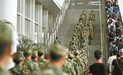 点击查看大图 尽管手里也有不少重物,武警官兵仍从电梯一侧的楼梯通过,不与旅客抢用电梯