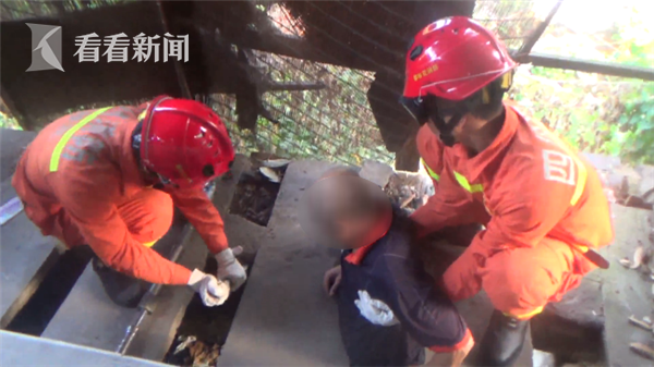 一名战士扶着老人,防止其进一步下滑,另外的消防官兵对水泥板进行破拆。