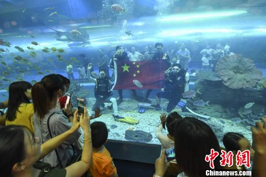 海洋城多名工作人员潜入海底隧道展开五星红旗庆国庆。 杨华峰 摄