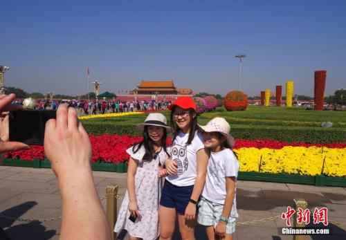 9月29日，三位小游客在北京天安门广场国庆花坛前留影。 中新社记者 贾天勇 摄