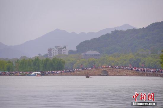 10月3日,国庆长假第三天,参观西湖断桥的游客络绎不绝。 中新社记者 李晨韵 摄