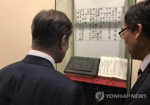 资料图片:文在寅(左)在出席联大期间参观陈列于联合国总部的《月印千江之曲》。(图片来源:韩联社)