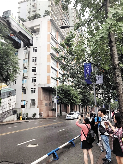 游客举着相机,等着列车穿楼而过|重庆|李子坝