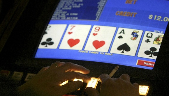资料图片:一名赌客在玩电子扑克(video poker)赌博机。来源:东方IC