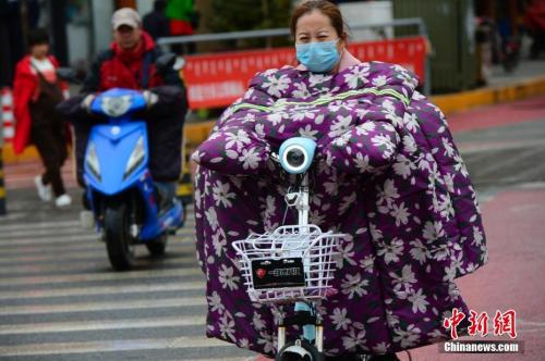 10月9日，内蒙古多地大幅降温，在呼和浩特街头，骑电动车的行人穿上“棉衣”出行。 中新社记者 刘文华 摄