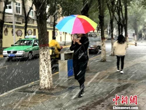 图为9日西宁市区飘起鹅毛般大雪，市民撑伞行走。 孙睿 摄