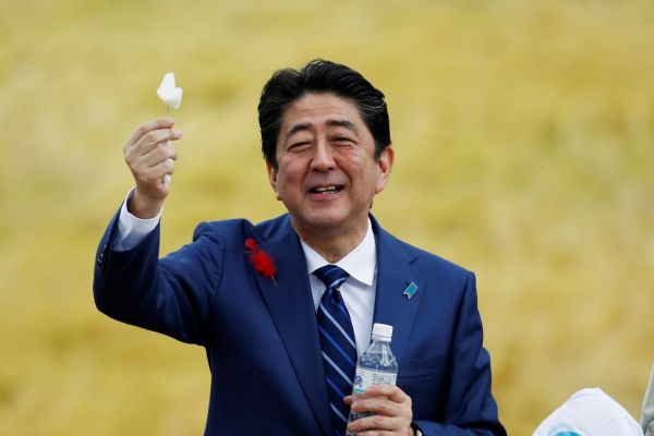 10月10日,日本首相安倍晋三在福岛的竞选集会上举着当地支持者送的一块梨。(路透社)