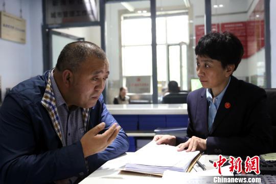 图为田小红在社区向前来办理事项的居民了解情况。 罗云鹏 摄