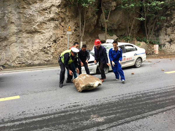 交警与路过驾驶员一道将石头搬开。