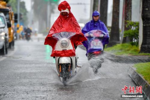 10月15日，海口民众雨中涉水骑行。中新社记者 骆云飞 摄