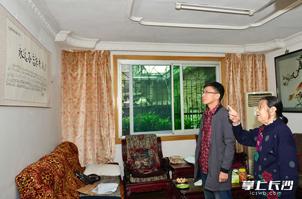李先质老人（右一）向学校老师介绍老伴李启瑞的书法作品“永远不忘挖井人”。 屈晓军摄