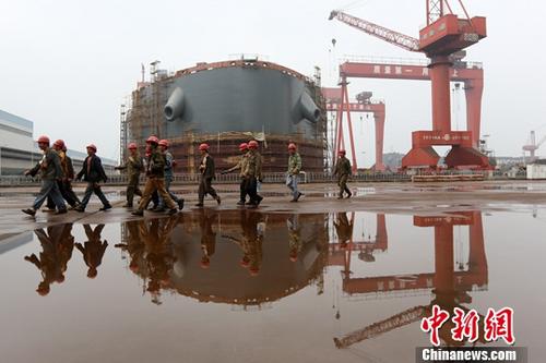 图为江苏泰州一家造船厂内,工人从正在建造的船前经过。(资料图片)中新社记者 泱波 摄
