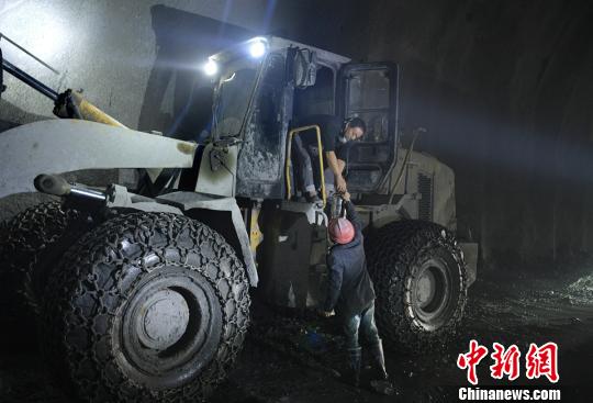 一名工友給開挖掘機(jī)的師傅送來午飯，為早日建成通車，挖掘機(jī)師傅車上吃飯，為隧道的打通爭取時間?！⒅铱　z