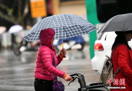 10月23日，昆明市区里身着羽绒服冒雨赶路的民众。 中新社记者 李进红 摄