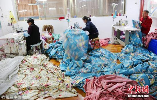 图为缝纫工在江苏省南通市一家家纺有限公司缝纫车间忙碌。 图片来源:视觉中国