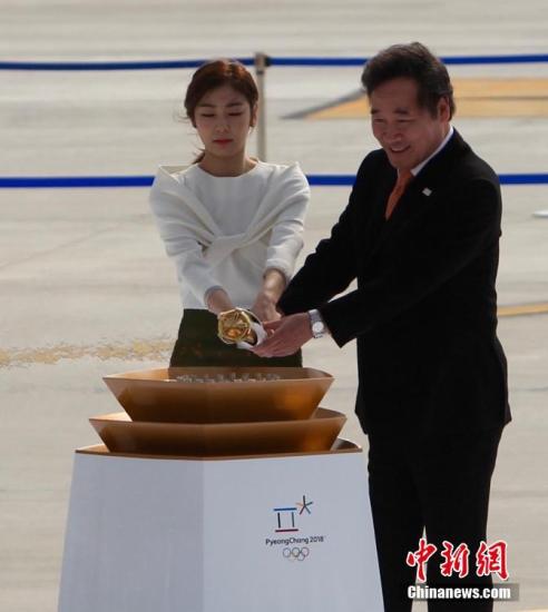 资料图:当地时间11月1日,2018年平昌冬奥会圣火抵达韩国仁川机场。图为圣火欢迎仪式上,平昌冬奥宣传大使金妍儿(左)与韩国国务总理李洛渊共同点燃圣火火炬。中新社记者 吴旭 摄