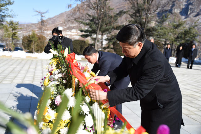 11月19日，在桧仓中国人民志愿军烈士陵园园内纪念碑前，宋涛整理花篮缎带。（新华社记者程大雨摄）