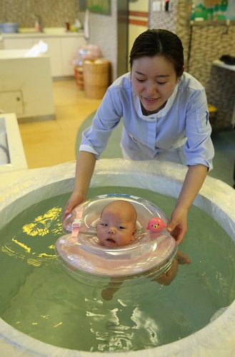 资料图片：2015年1月30日，一名母婴家庭保健师在上海一家月子会所内带婴儿游泳。新华社记者 丁汀 摄