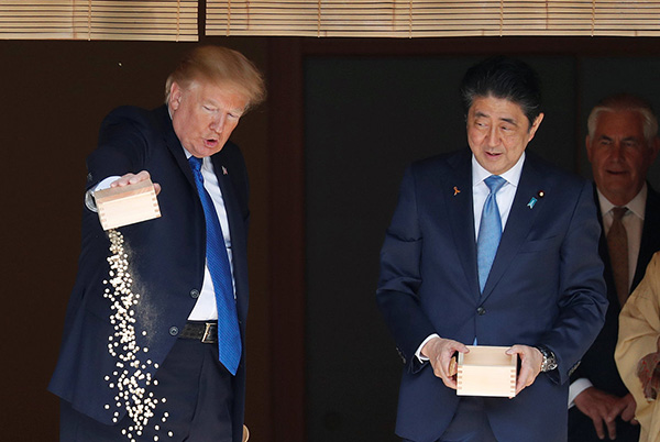 当地时间2017年11月6日,日本东京,日本首相安倍晋三与美国总统特朗普在工作午餐前一起喂锦鲤。视觉中国 资料