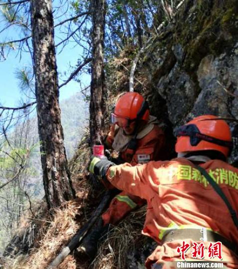 陡峭的山坡上消防員們相關幫助。 曹雲鵬 攝