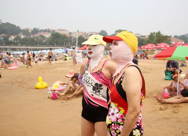 在青岛第一海水浴场，游泳的人们戴上“脸基尼”防晒。