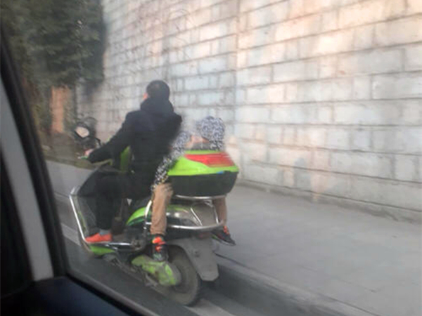 男子载娃反坐电瓶车 小孩趴在货箱呼呼大睡