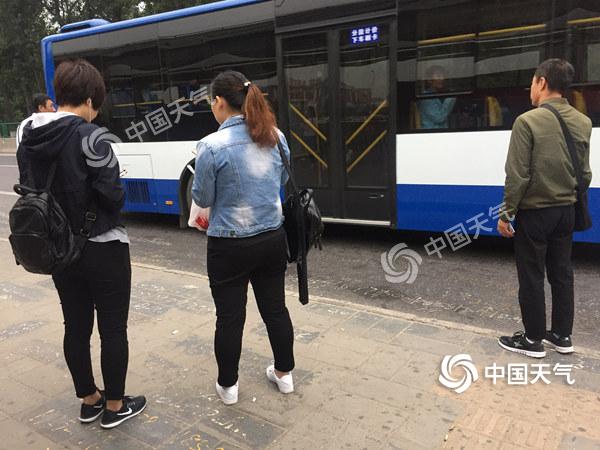 清晨气温较低,候车乘客都已穿起一身秋装。(关禺/摄)