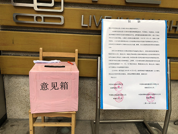  小区正门口摆放着运营商的告示，以及业主自主投票意见箱。澎湃新闻记者 陈凯姿 图