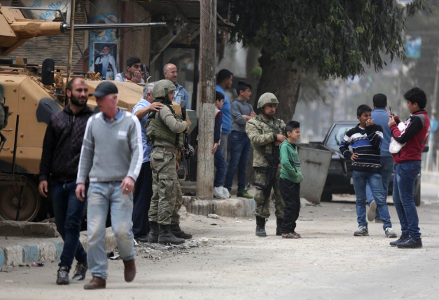2018年3月24日，一名男孩在叙利亚阿夫林地区中心为土耳其士兵和人们拍合照。（图源：路透社）