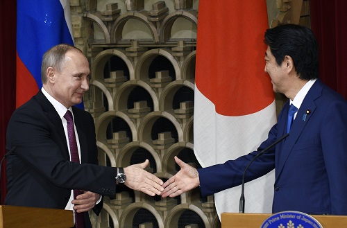 2016年12月16日，在日本东京首相官邸，日本首相安倍晋三（右）与俄罗斯总统普京共同会见记者时握手。 新华社发
