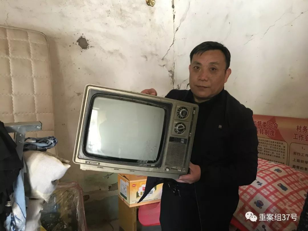 ▲周继坤抱着一台黑白电视机。1996年事发当天，这台电视里播放着一部香港影片。