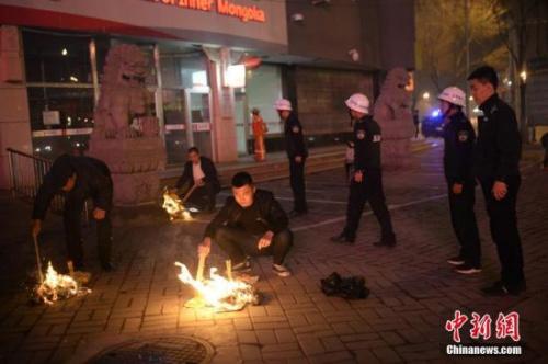 资料图：城管执法人员劝阻民众停止在街边焚烧纸钱。中新社记者 刘文华 摄