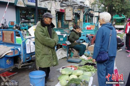 9月7日,黑龙江黑河,大早市上卖菜农民穿着棉衣和羽绒服。邱齐龙 摄 图片来源:视觉中国