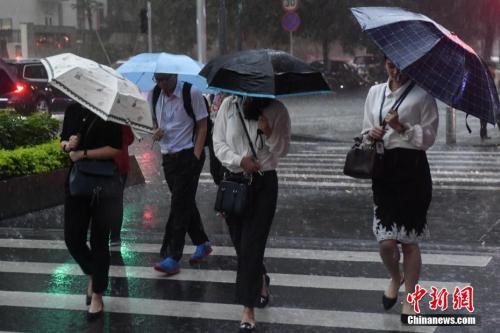 资料图：5月7日，广州街头，民众撑伞行走在雨中。中新社记者 陈骥旻 摄