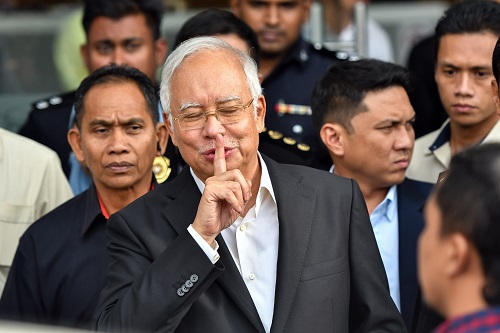 2018年5月24日，在马来西亚普特拉贾亚，马来西亚前总理纳吉布（前）接受问话后离开反腐败委员会。新华社发（张纹综摄）