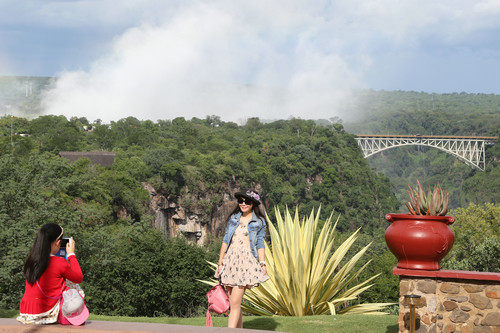 资料图片：2017年1月27日，在津巴布韦维多利亚瀑布城，来自中国的一对母女以远处的赞比西铁桥为背景拍照留念。新华社发