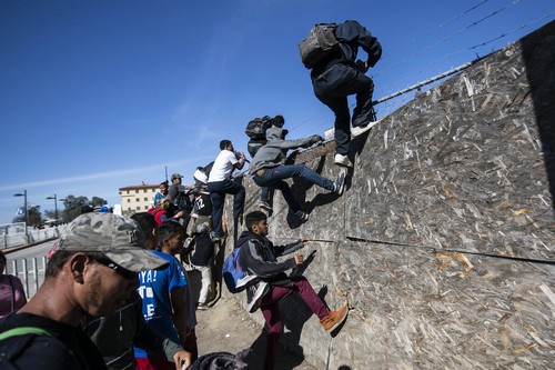 一些移民11月25日在墨西哥下加利福尼亚州蒂华纳试图翻越障碍到达美墨边境（法新社）