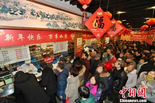 资料图:民众排长队购熟食备年货。宦玮 摄