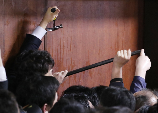 韩国执政党议员试图用工具撬门，进入被封锁的国会会场。（韩国《中央日报》）