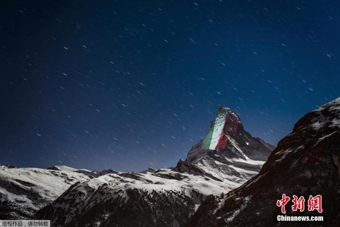 资料图：当地时间4月1日，瑞士阿尔卑斯山脉标志性的马特洪峰出现灯光投影的巨大横幅，在疫情中呼吁“希望和团结”。图为灯光在马特洪峰山顶映出意大利国旗。