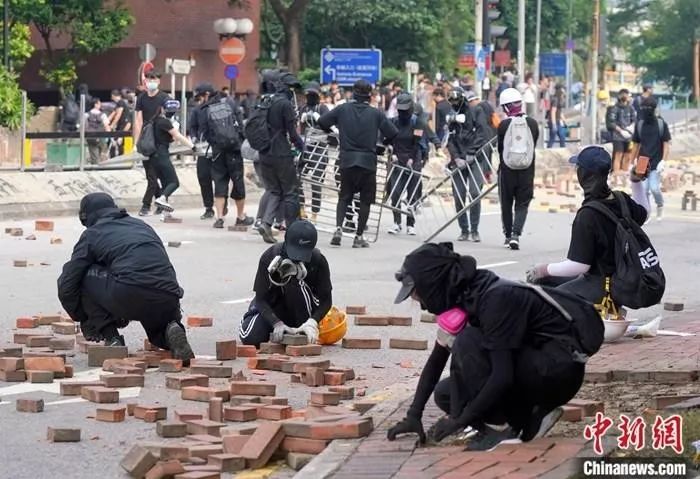  11月14日下午，众多蒙面黑衣人在香港理工大学对出的畅运道设置路障，挖掘人行道上的砖块堵塞道路。中新社记者 张炜 摄