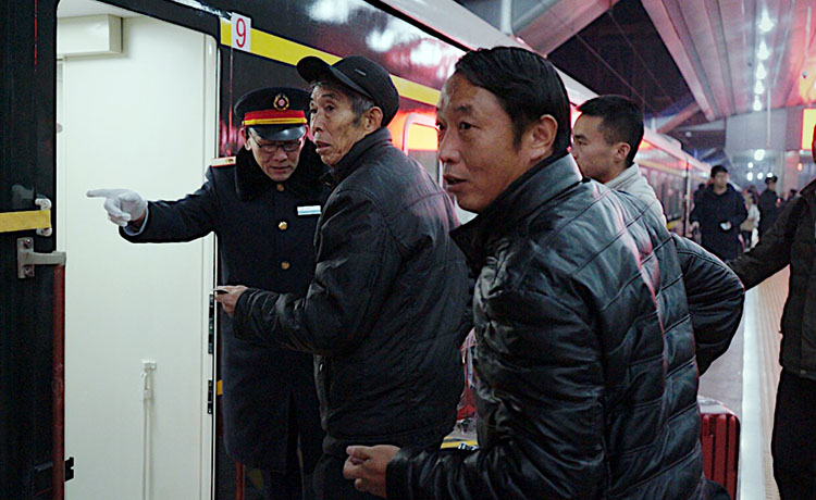 1月21日凌晨，北京火车站，K4051次列车前，列车员指引乘客。