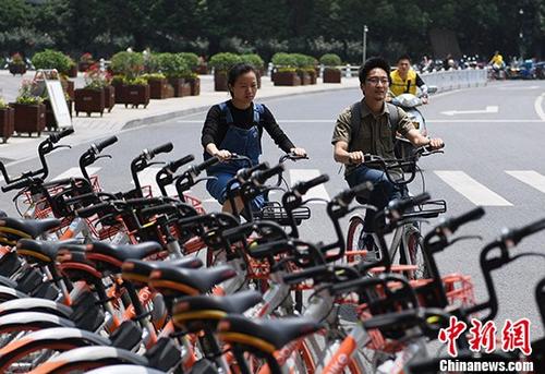 资料图：两名市民正在从摆放的共享单车前骑过。 中新社记者 王刚 摄