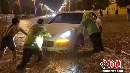 暴雨中交警等将熄火轿车推离险境。　刘忠俊 摄