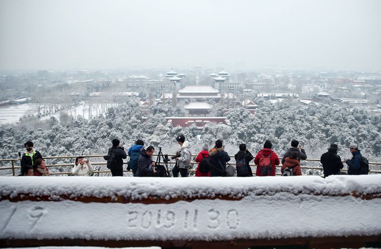 游客们在拍摄雪后的中轴线。