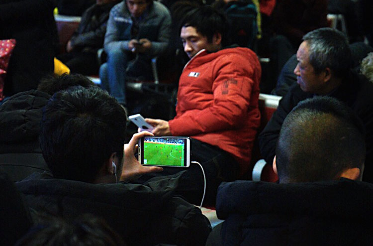 1月20日晚，北京火车站候车室，一名男子在观看亚洲杯中国对泰国的直播。