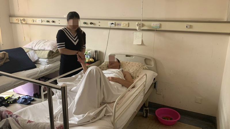 躺在病床的卢忠敏目前不能行走,家人正在对他的右手进行康复帮助。受访者供图